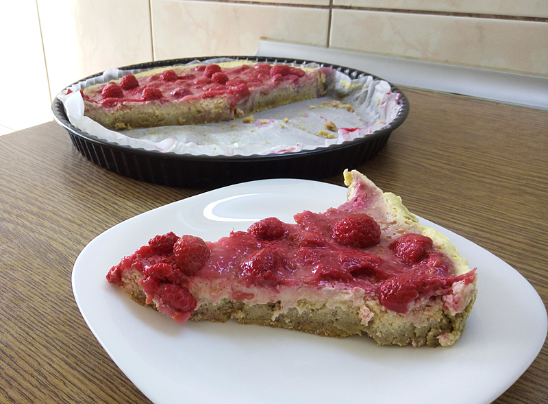 Slice of GF, SF, egg-free mango cheesecake with raspberry topping