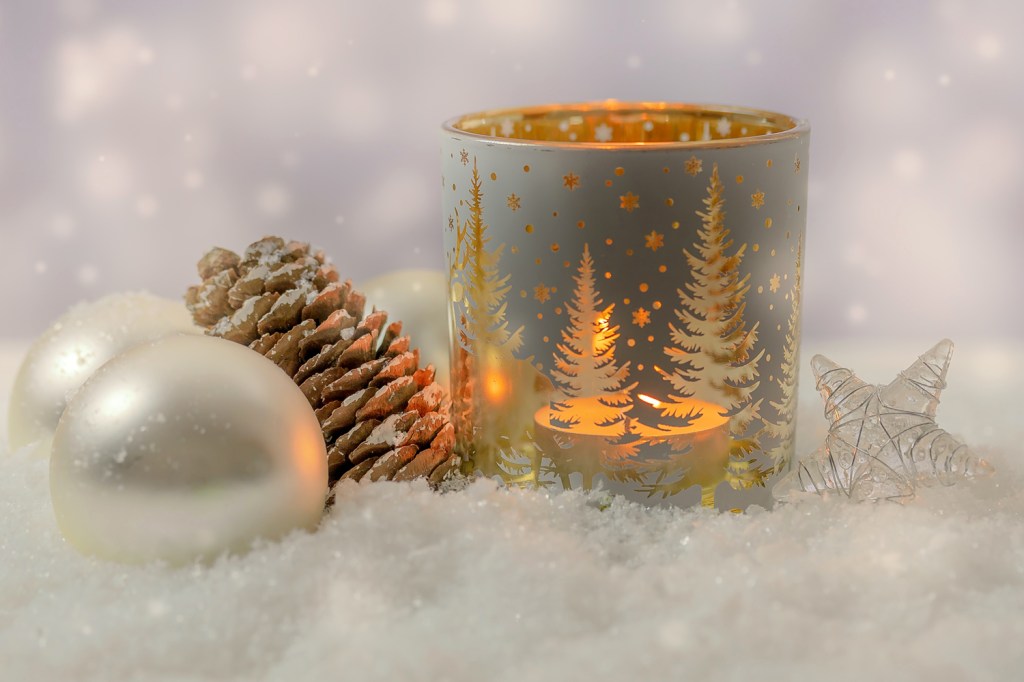 Christmas candle holder with fir trees, a pine cone, a star, and two white baubles in the snow