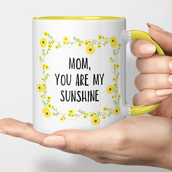 White mug dyed yellow inside with the words "Mom, you are my sunshine" inside a floral frame.