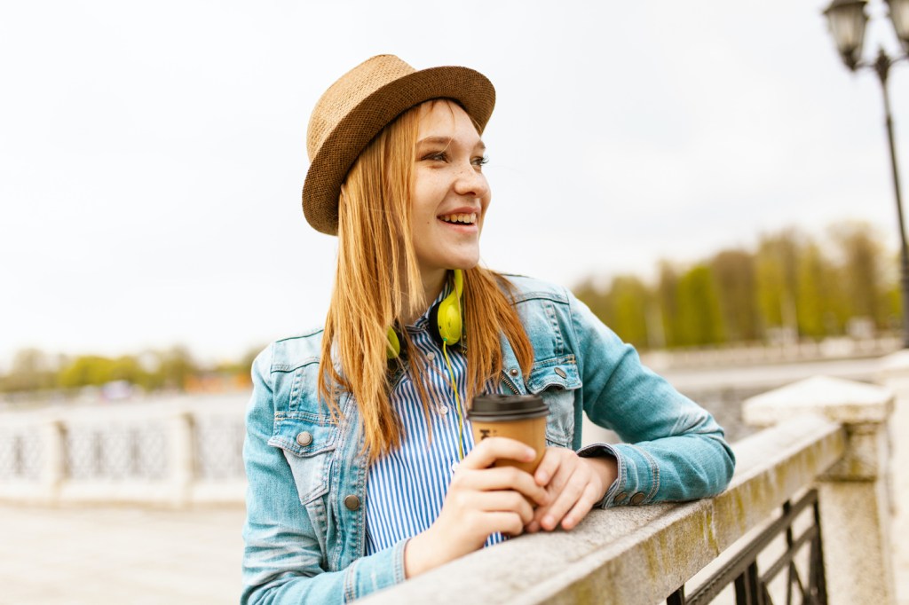 Young freckled ginger-haired woman wearing a sunhat and looking into the distance with a smile on her face