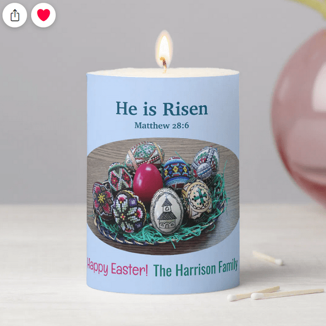 Religious pillar candle for Easter with the Bible verse for Christ has Risen and "Happy Easter!" along with a personalized family name. With a basket of decorated Easter eggs