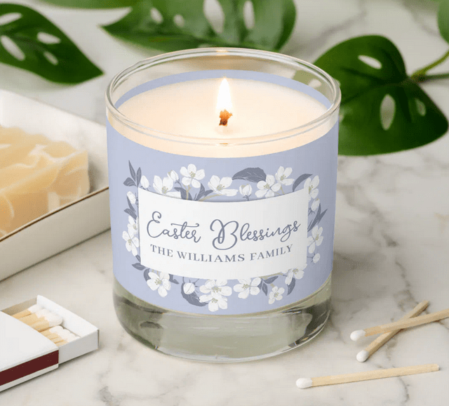 Vanilla sandalwood scented candle, personalized for a religious Easter, with the words Easter Blessings and a family name. With beautiful white tree blossoms on a blue gray pastel background